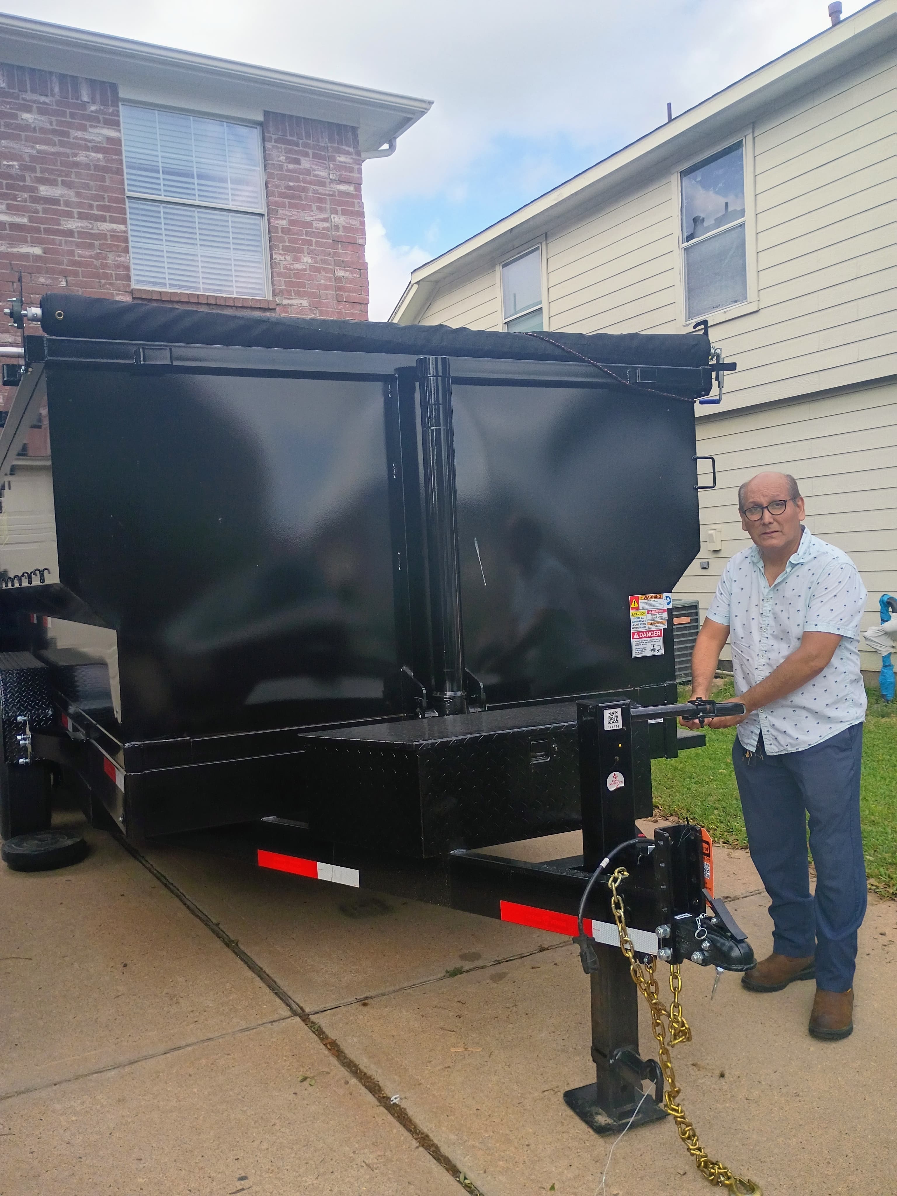 Owner standing beside the 16 foot dump trailer in Houston after delivery to show the actual rental equipment.
