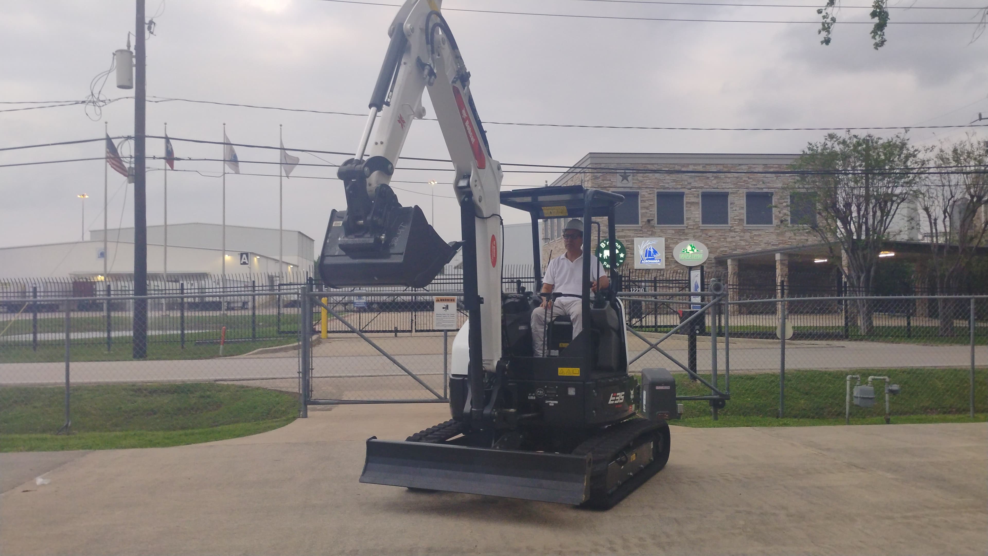 Bobcat E35 compact excavator at the Houston yard with the boom raised and operator seated in the cab.
